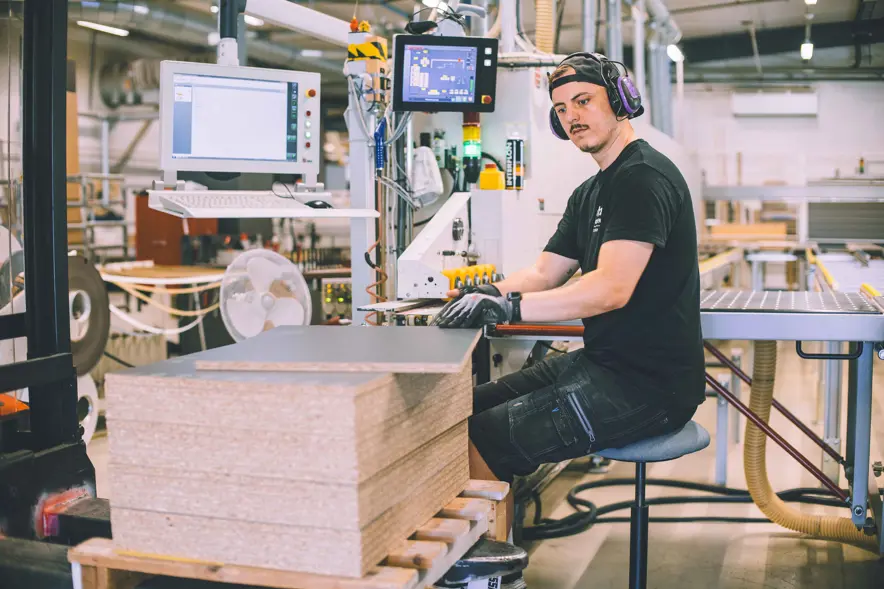 Familien Tobiassen har valgt å investere og bygge opp lokalt. Strai kjøkken sysselsetter 190 ansatte, og har stadig fornyet produksjonen for å være konkurransedyktige. Her ser vi sponplater i ferd med å  bli del av produksjonslinjen, hvor de skal få kantlist.